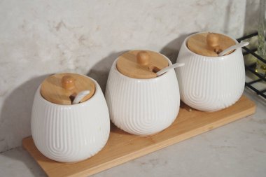 Tepsiye ahşap kapaklar konmuş üç şık baharat kavanozu..