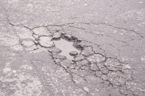 Suyla dolu büyük bir çukur şehrin kaldırımlarını bozuyor..