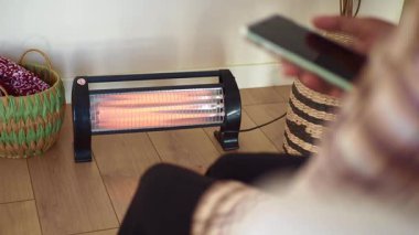 İçerde akıllı telefon kullanırken ısıtıcının sıcaklığının tadını çıkarıyorum..