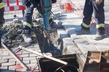 İnşaat işçileri kaldırımda tamir için kaya matkabı kullanıyorlar..