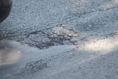 Derin bir çukur, şehrin asfalt yol yüzeyini bozar..
