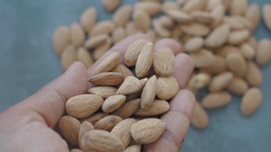 Bir insan sağlıklı bir atıştırmalık yaparken taze badem sergiler..