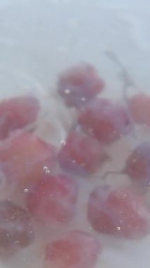 kırmızı üzümler bir kase suya düşer, yavaş çekimde. ,
