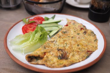 Taze salatalık ve domates dilimleriyle sergilenmiş lezzetli bir sebze omleti..