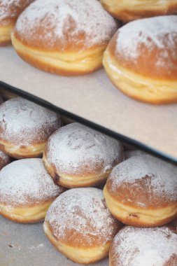Taze pişmiş hamur işleri pudra şekerle tozlanmış tepsilerde oturuyorlar..