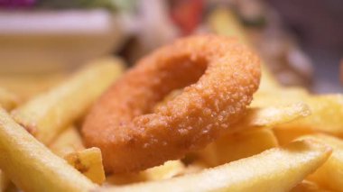 İştah açıcı bir soğan halkası çıtır çıtır altın kızartmaların üzerinde oturur..