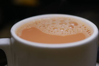 Kapalı alanda köpüklü yüzeyi olan bir fincan sıcak çayın yakın görüntüsü..