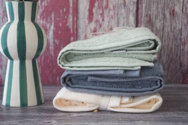 Dekoratif vazonun yanına çeşitli renklerde katlanmış havlular..