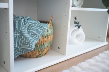 Dokuma sepetinde modern bir rafta rahat bir battaniye var..