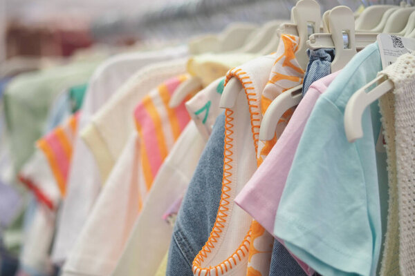 Различные типы одежды выставляются на вешалках в магазине.