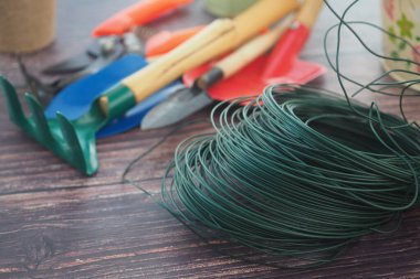 Bahçe aletleri ve yeşil kablolar ahşap bir masaya dizilir..