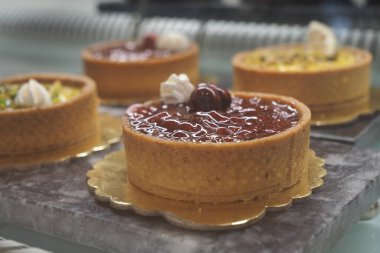 Renkli malzemeli çeşitli meyveli turtalar bir fırında sergileniyor..