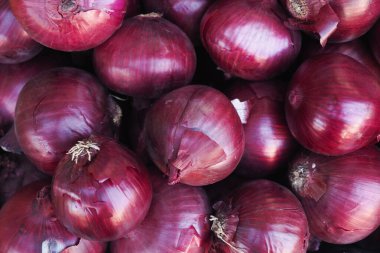 Açık hava pazarında parlak kırmızı soğanlar üst üste yığılır..