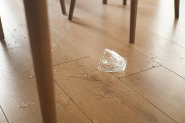 Bir cam yan yatar, ahşap zemine su döker..