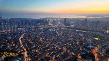 Gün batımı ufku boyarken canlı bir şehir manzarası..