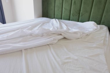 Çağdaş bir odada düzgünce yapılmış bir yatakta kırışık beyaz yatak..