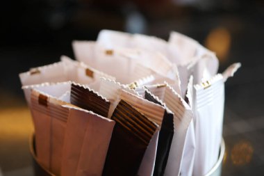 Şeker ve tatlandırıcı paketleri masanın üzerinde bir tutacağa yerleştirilmiş..