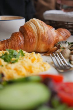 Kruvasan, yumurta ve sebzelerle yayılmış ağız sulandıran bir kahvaltı..