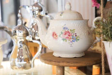 Çiçek desenli güzel işlenmiş bir çaydanlık ahşap bir yüzeye oturur..