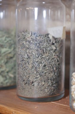 Ahşap bir yüzey üzerinde cam kavanozlarda çeşitli kurutulmuş bitkiler depolanır..