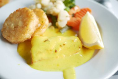 Lezzetli bir tabakta soslu deniz ürünleri, çıtır kekler ve taze sebzeler yer alır..