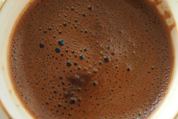 Kabarcıklı koyu kahve, sıcak bir kupada köpük zenginliği gösterir..