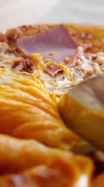 Bir pizzanın dilimlendiği, zengin malzemelerin ve peynirin sergilendiği yakın çekim görüntüsü..