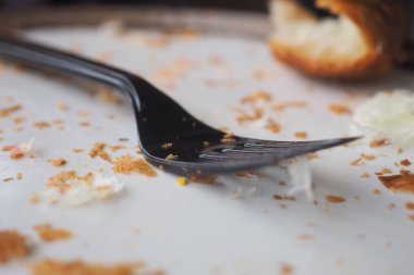 Kullanılmış bir çatal yemekten sonra kırıntıların yanına oturur..