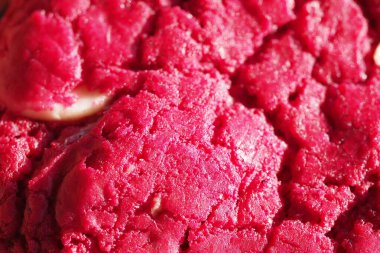 Canlı kırmızı bir kurabiyenin yakın plan görüntüsü. Işığın yansımasıyla pürüzlü bir yüzeyi gösteriyor..