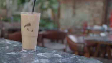 Çevresindeki yeşilliklerle birlikte açık bir kafede buzlu kahve bir masada duruyor..