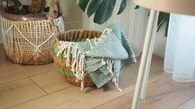 Dekoratif dokuma sepetinde parlak bir odada desenli bir battaniye bulunur..