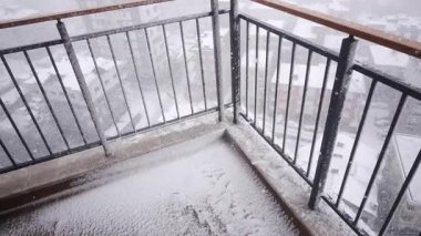 Şiddetli kar yağışlı bir balkon ve kışın şehir sokaklarını kaplıyor..