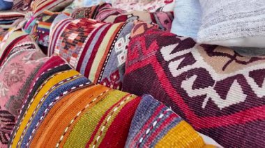 Hareketli bir pazarda sergilenen el dokuması kumaşlar..
