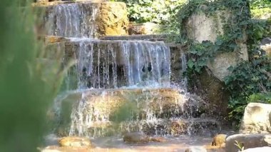 Bahçedeki kayaların üzerinden akan suyun rahatlatıcı seslerinin tadını çıkar..