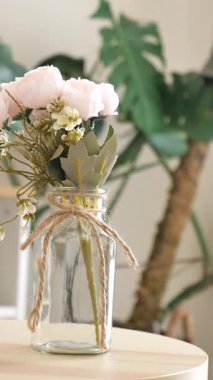 Cam bir kavanozdaki güzel pembe çiçekler rahat bir yeri aydınlatır..