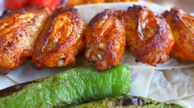 Taze sebzelerle servis edilen lezzetli ızgara tavuk kanatlarının keyfini çıkarın..