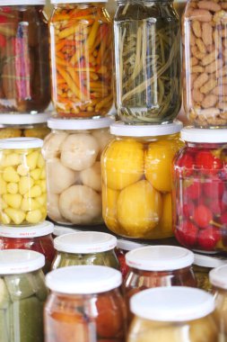Colorful jars filled with various preserved fruits and vegetables are lined up.
