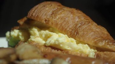 Çırpılmış yumurta ve sebzelerle dolu lezzetli bir kahvaltılık kruvasanın tadını çıkarın..