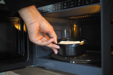 El mikrodalgaya yemek pişirmek için bir tabak koyar..