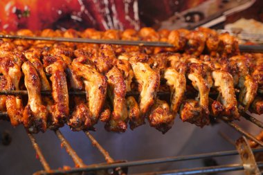 Meşgul bir pazar ortamında ızgarada pişen sulu tavuk şişleri..