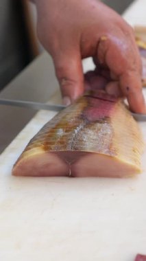 Becerikli bir el, yerel bir markette ustalıkla balık doğruyor..