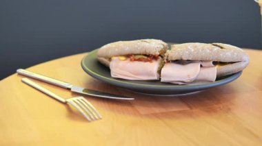 Taze yapılmış sandviç, ahşap bir masada malzemelerle servis ediliyor..