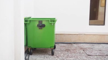 Yeşil bir çöp kutusu bir binanın yakınındaki sakin bir avluya konur..