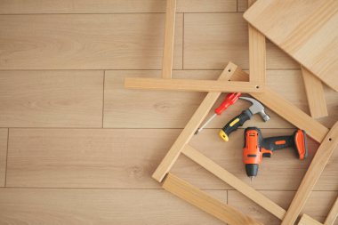 Çeşitli aletler ve ahşap sandalyeler yere saçılmış..