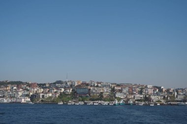 Parlak güneş ışığı, hareketli bir şehirde, suyun kenarında, sallanan teknelerle parlıyor..