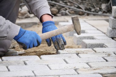 Bir inşaat işçisi yere tuğla yerleştirmek için tokmak kullanır..