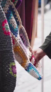 Bir el, el işi pazarında renkli tığ işi yamaları inceler..