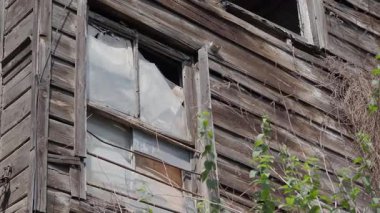 Güneşli bir günde kırık camlı eski bir ahşap yapı..