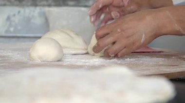 Eller, meşgul bir mutfakta hamur pişirmek için ustalıkla şekillendiriliyor..