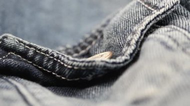 Dikiş ve düğme detaylarını vurgulayan kot kumaşının yakın görünümü.